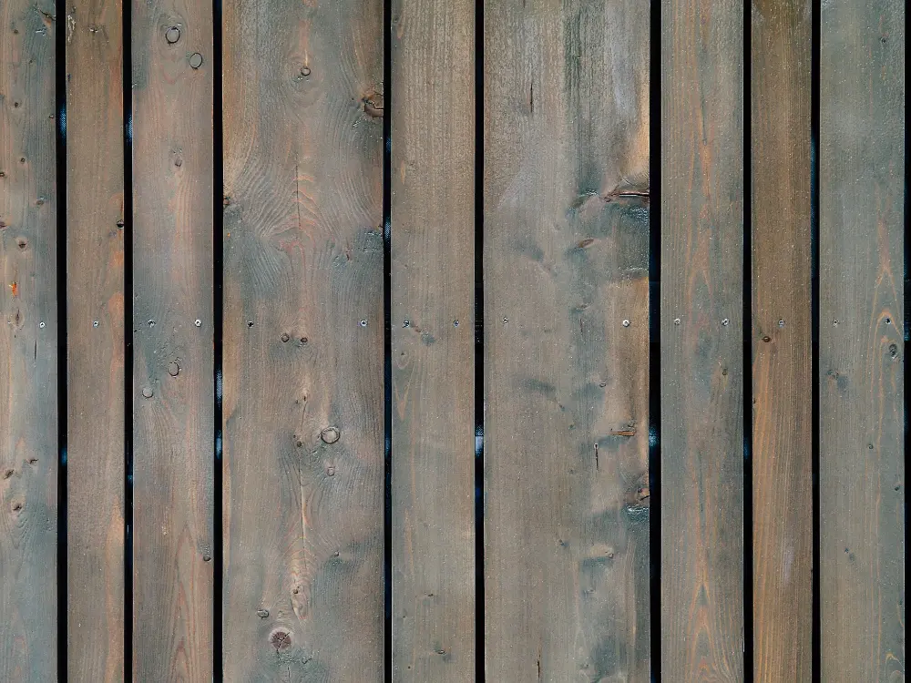 Zbliżenie pionowych drewnianych desek ogrodzeniowych z widocznym usłojeniem, sękami i niewielkimi szczelinami między deskami. tarasy szczecin