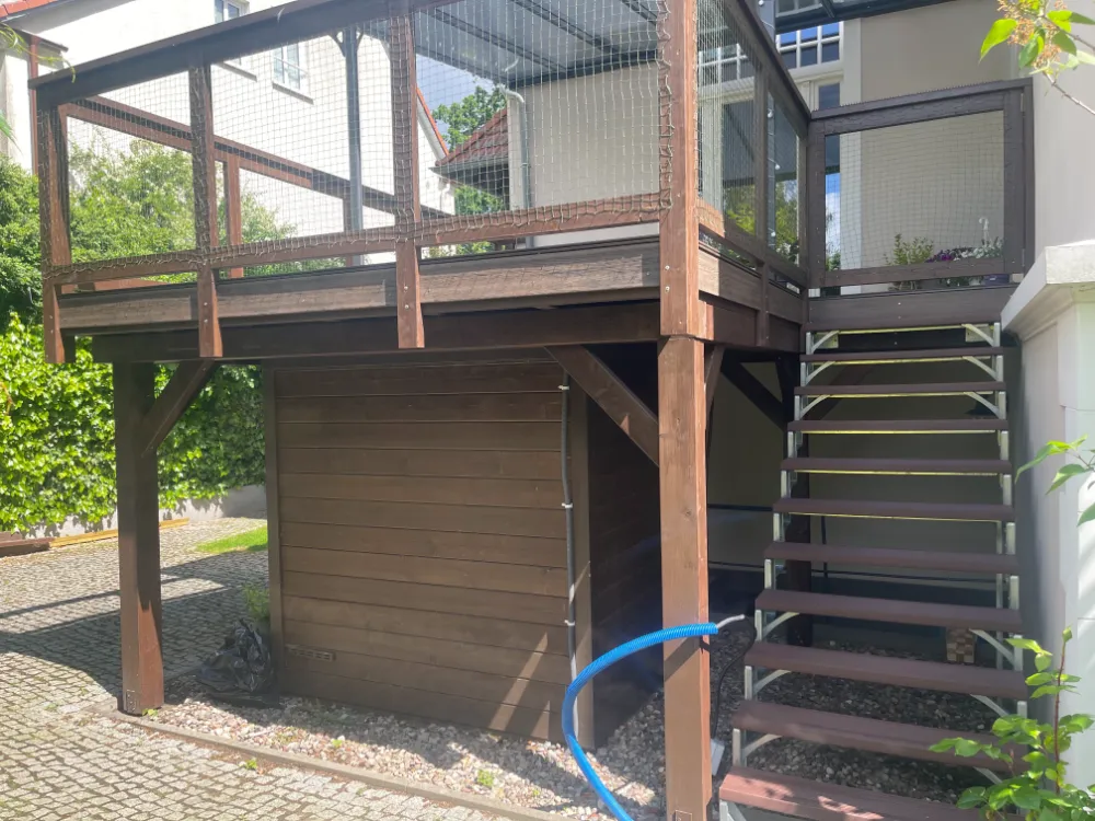 Drewniany taras z drucianą balustradą, schodami i schowkiem pod spodem obok domu. tarasy szczecin